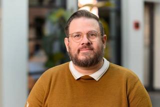a man with glasses and a beard sitting in a chair